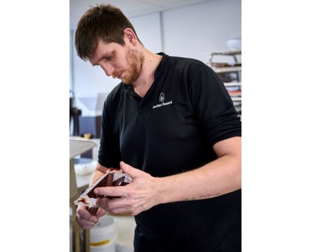 Chocolatier Aurélien Plassard handling a chocolate creation in his workshop.