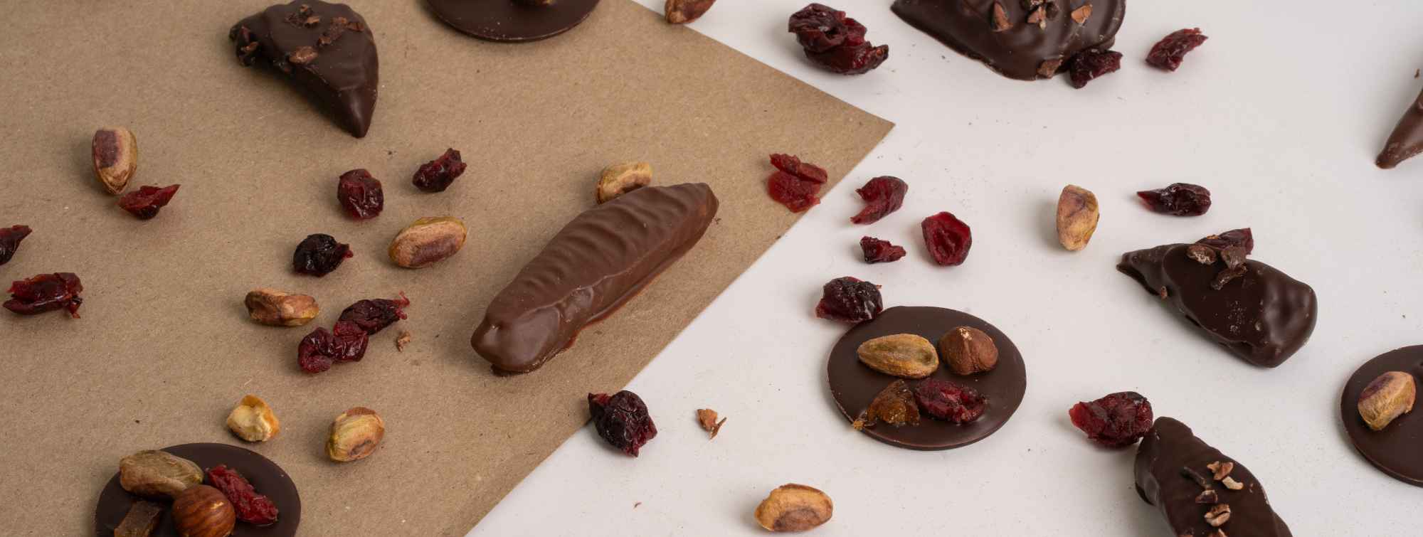 Assortiment de chocolats noirs artisanaux garnis de pistaches, de fruits secs et de cranberries.
