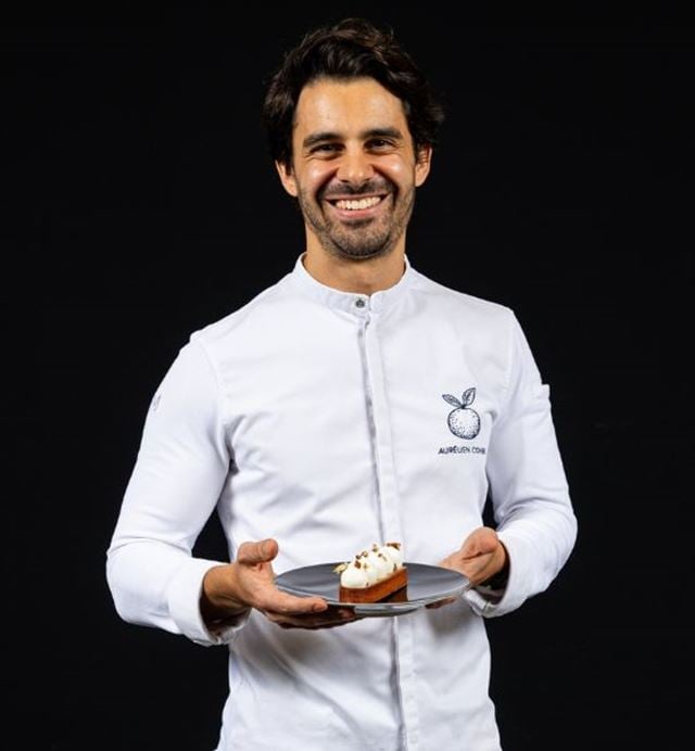 Portrait of a pastry chef presenting a gourmet dessert on a black background