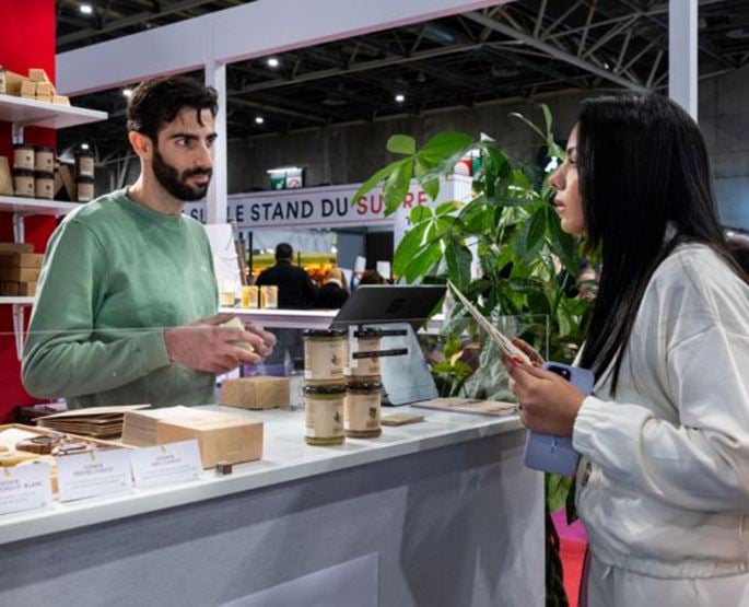 Échange entre un jeune exposant et une visiteuse sur l’espace Jeunes Talents du Salon du Chocolat