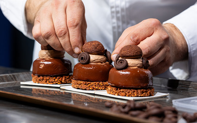 Démonstration d'une recette en live sur la scène du Pastry Show avec mise en avant d'une pâtisserie au chocolat.