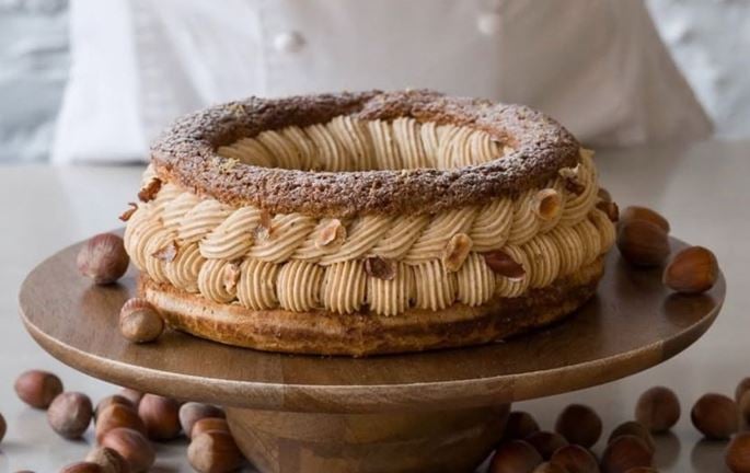 Cream-filled pastries topped with flaked almonds, displayed on white paper.