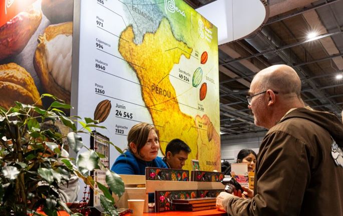 Visiteur échangeant avec des exposants devant une carte du Pérou présentant ses régions productrices de cacao au Salon du Chocolat.