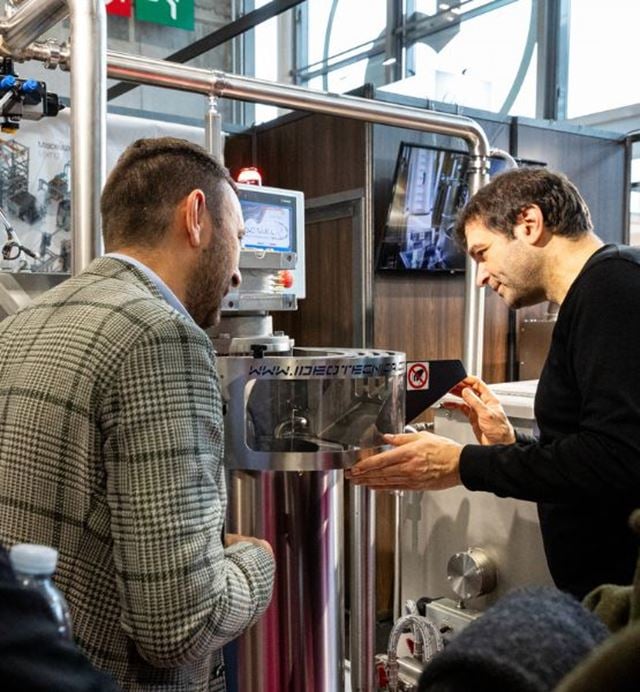 Démonstration d’une machine industrielle avec deux professionnels observant un équipement technologique sur un salon